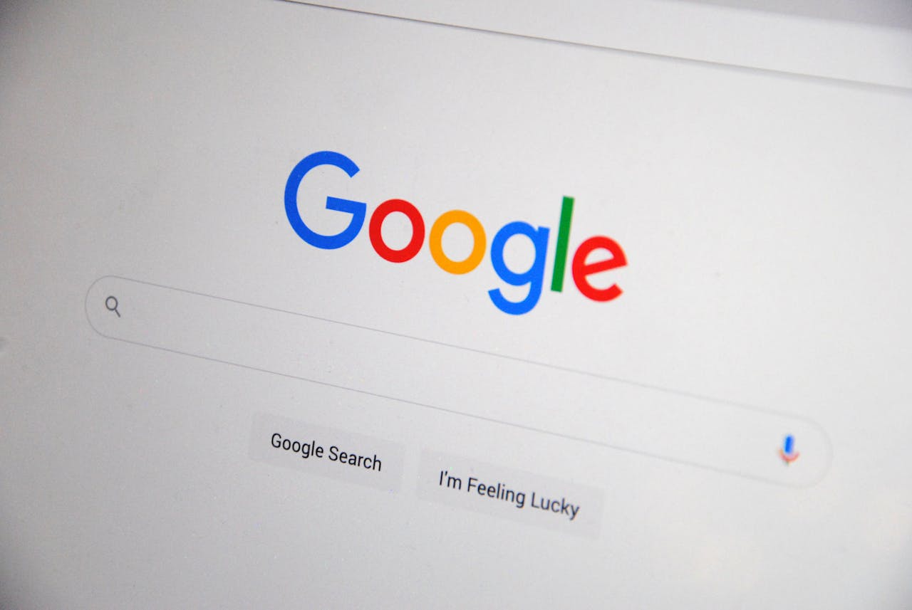 services-02 Close-up of the Google homepage on a screen showing search options.